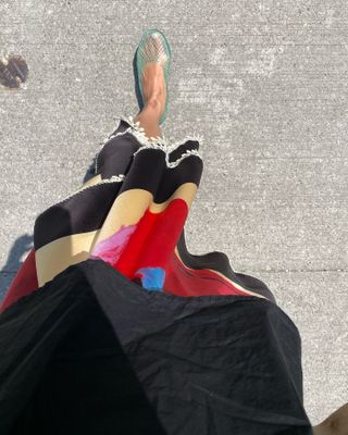 overhead view of fashion influencer Sasha Mei's feet wearing jelly sandals and a colorful midi skirt