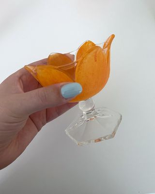 Beauty editor Kaitlyn McLintock holding an orange cup with light blue nail polish